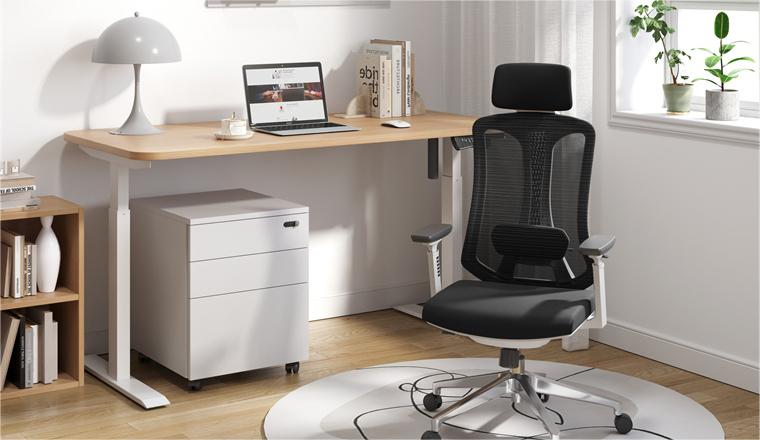 A home office ergonomic chair with a black mesh back and black seat. Along with a maple standing desk and a white cabinet 